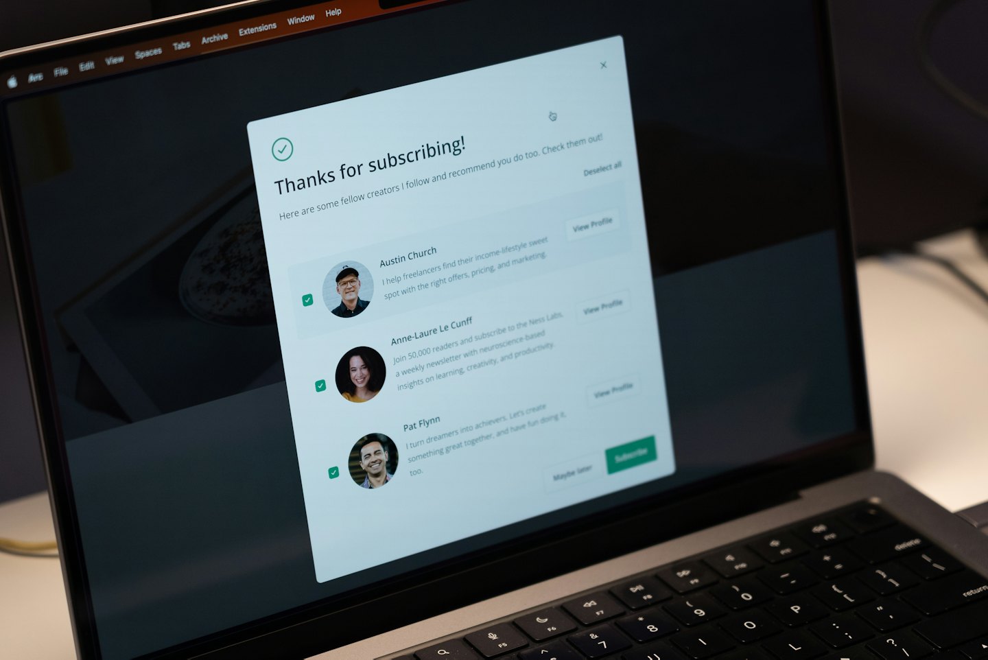 Laptop screen shows subscription confirmation with creator recommendations.